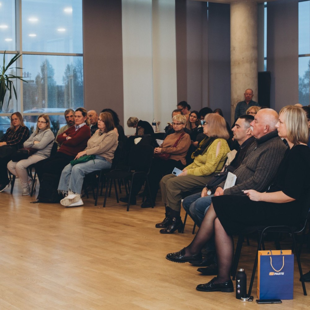 1728549515634 divi vīrieši sēž zāles priekšā