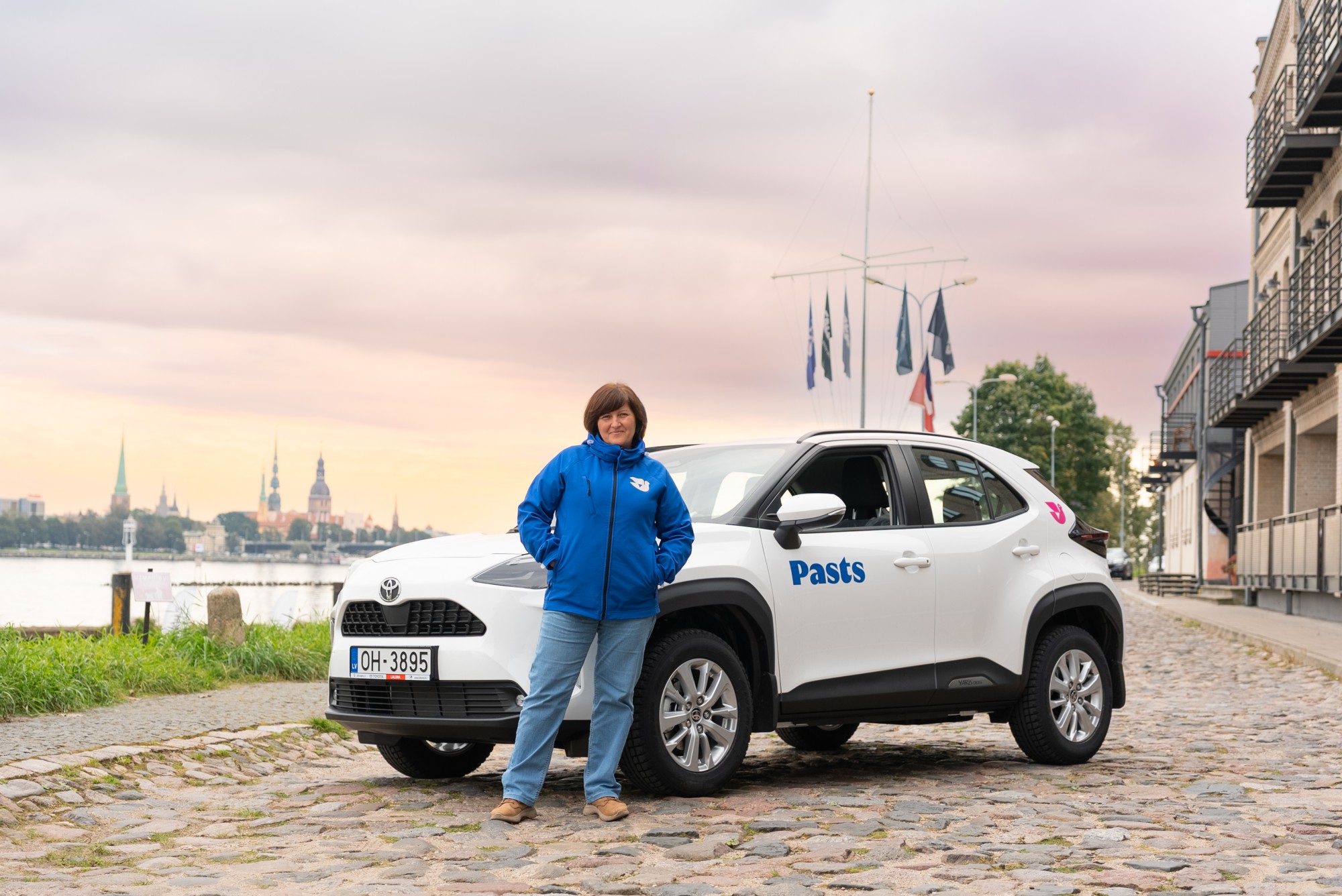 Pastniece stāv pie auto